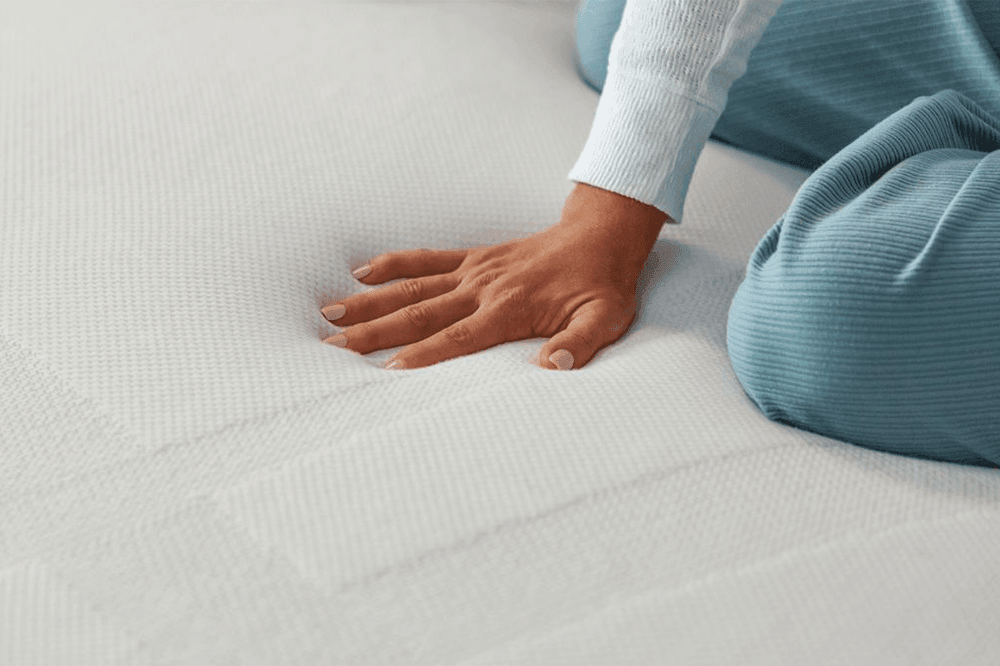woman's hand pressing down on adapt mattress topper