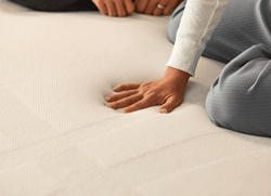 A woman's hand pressing on the the Adapt topper