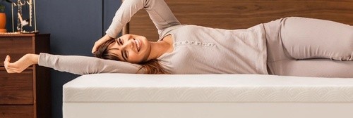 A Woman laying on bed with Cloud Topper